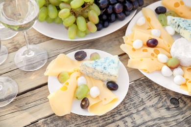 Wine, cheese and grapes on wooden table. Vineyard picnic