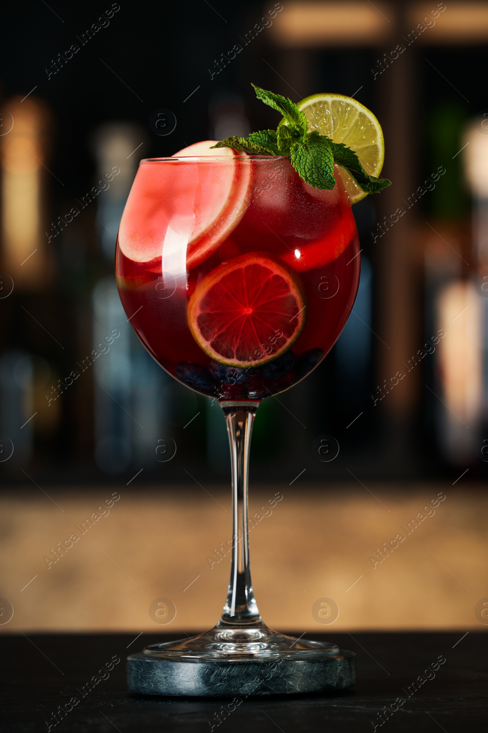 Photo of Delicious sangria cocktail on black table in bar