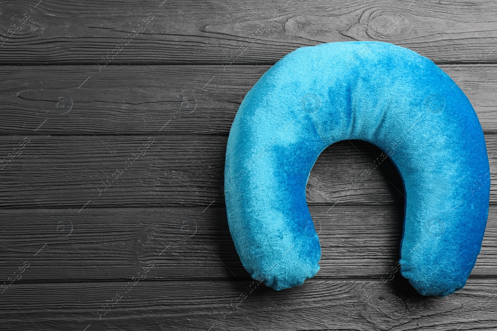 Image of Blue travel pillow on wooden background, top view. Space for text