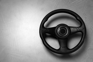 New black steering wheel on grey table, top view. Space for text