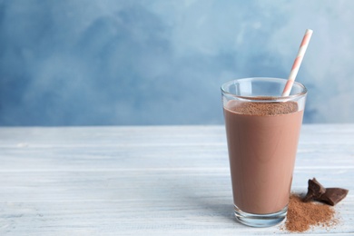Photo of Glass with tasty chocolate milk on wooden table, space for text. Dairy drink