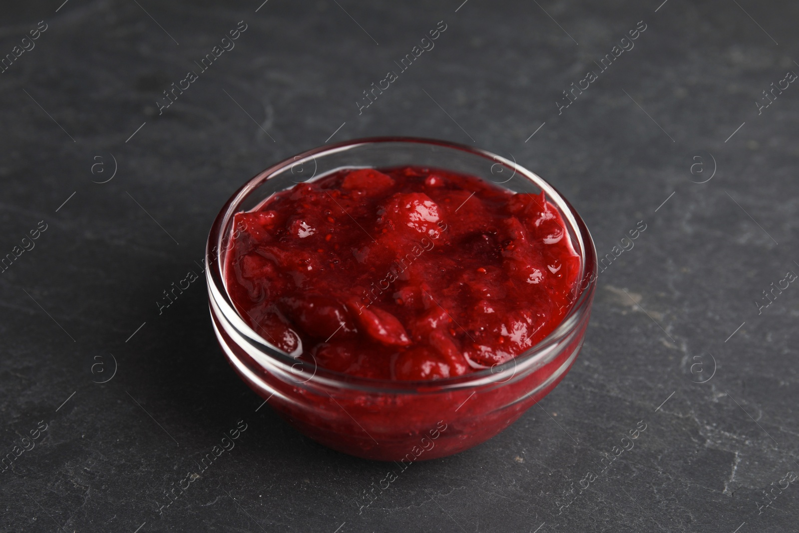 Photo of Bowl of cranberry sauce on grey background, closeup