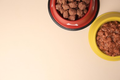 Wet pet food in feeding bowls on beige background, flat lay. Space for text