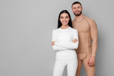 Photo of Man and woman in warm thermal underwear on grey background. Space for text
