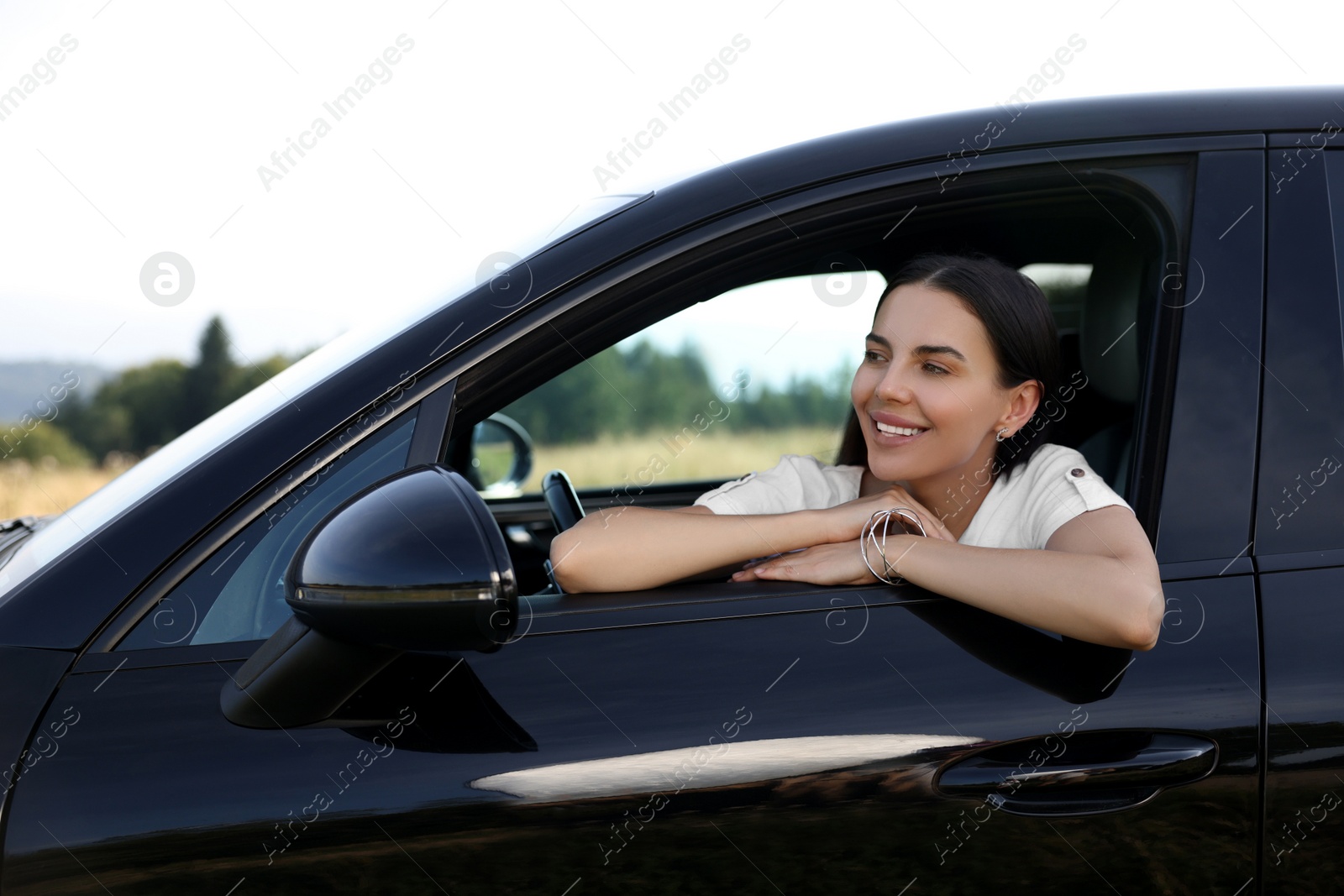 Photo of Enjoying trip. Portrait of beautiful happy woman in car, view from outside