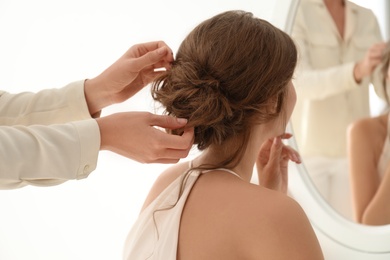 Hair stylist preparing bride for her wedding indoors