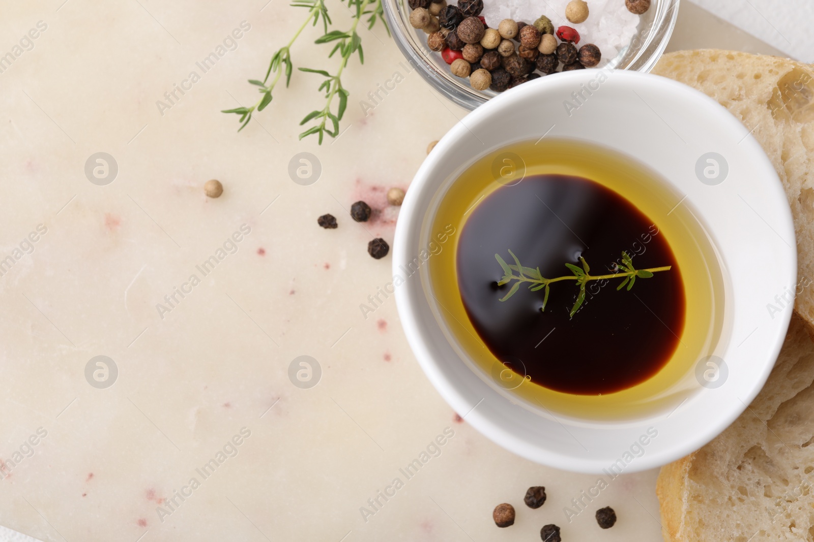 Photo of Bowl of organic balsamic vinegar with oil and spices served with bread slices on beige table, flat lay. Space for text