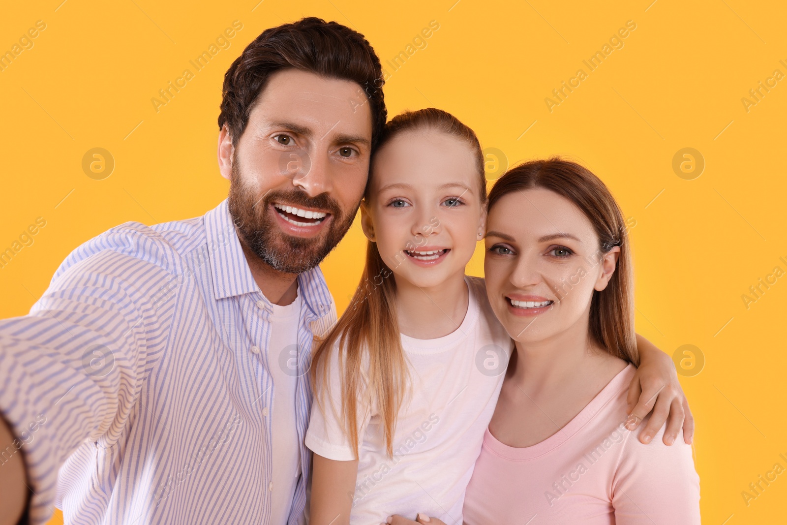 Photo of Happy family taking selfie on orange background