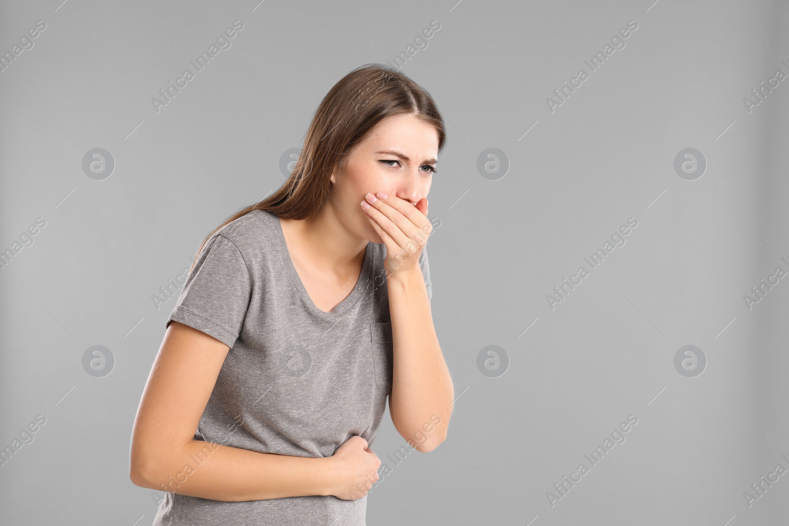 Photo of Woman suffering from nausea on grey background, space for text. Food poisoning