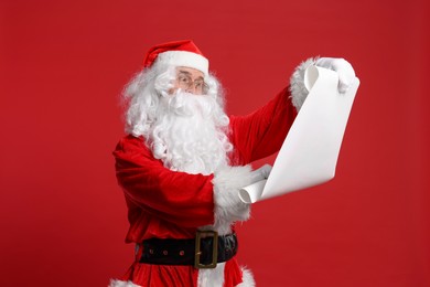 Photo of Merry Christmas. Santa Claus reading wishlist on red background