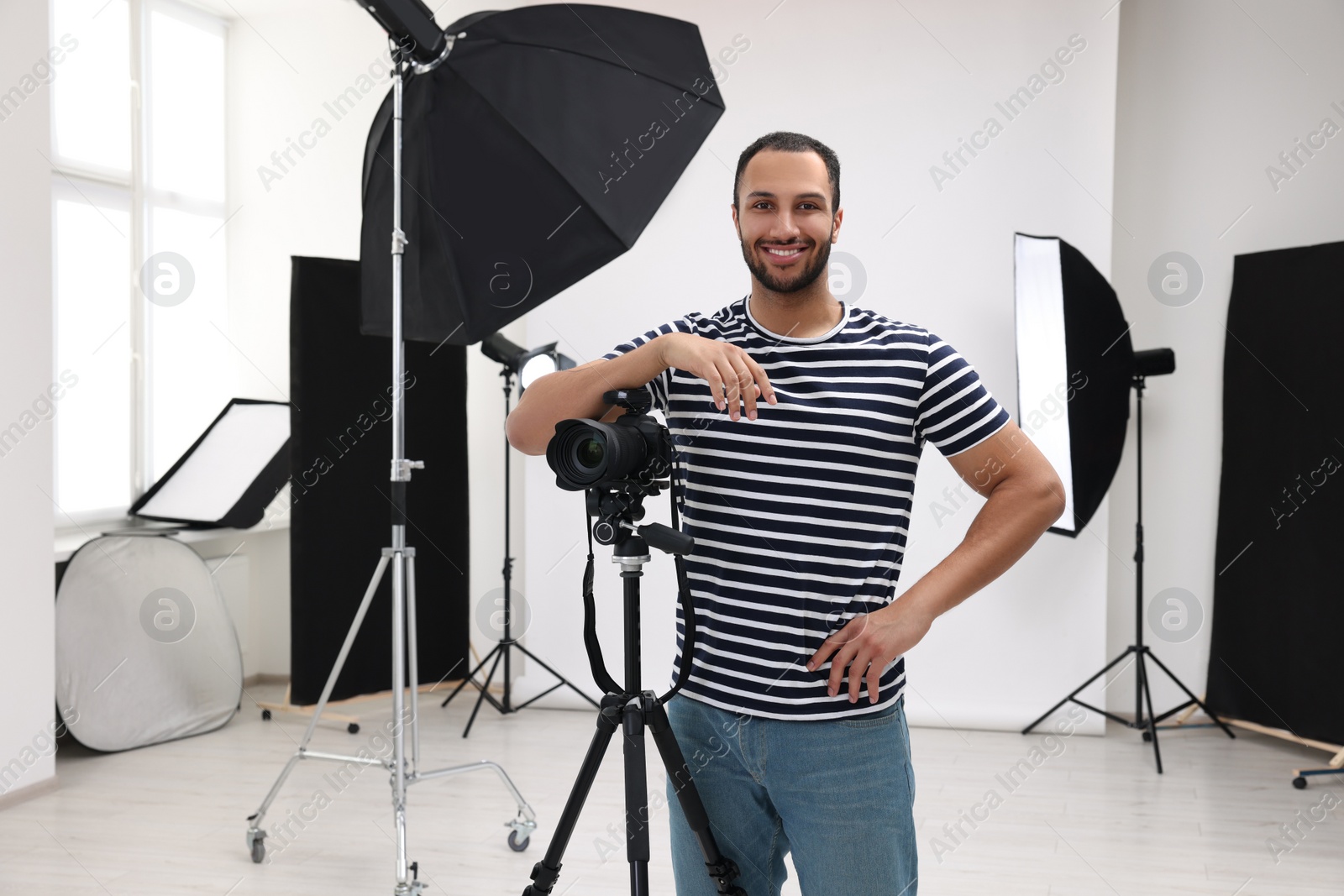 Photo of Young professional photographer with camera in modern photo studio