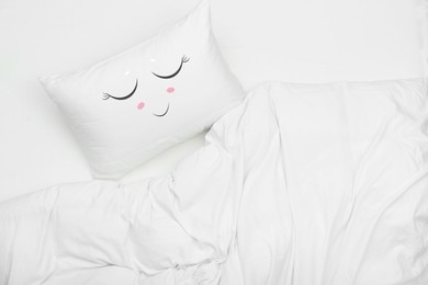 Image of Soft pillow with cute face and blanket on bed, top view