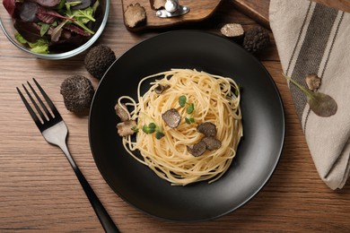 Photo of Tasty spaghetti with truffle served on wooden table, flat lay
