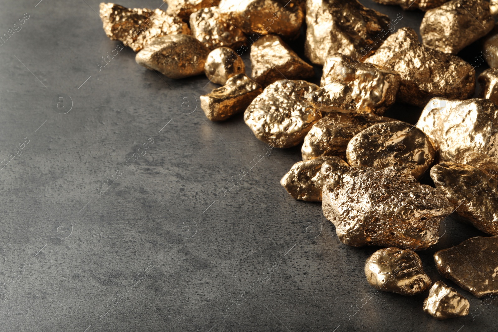 Photo of Pile of gold nuggets on grey table, space for text