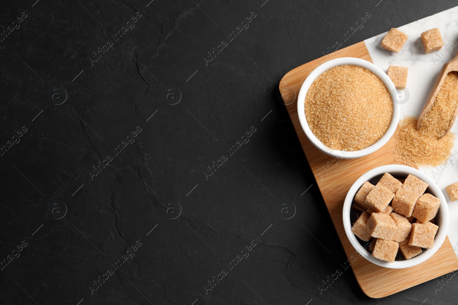 Photo of Brown sugar and board on black table, top view. Space for text