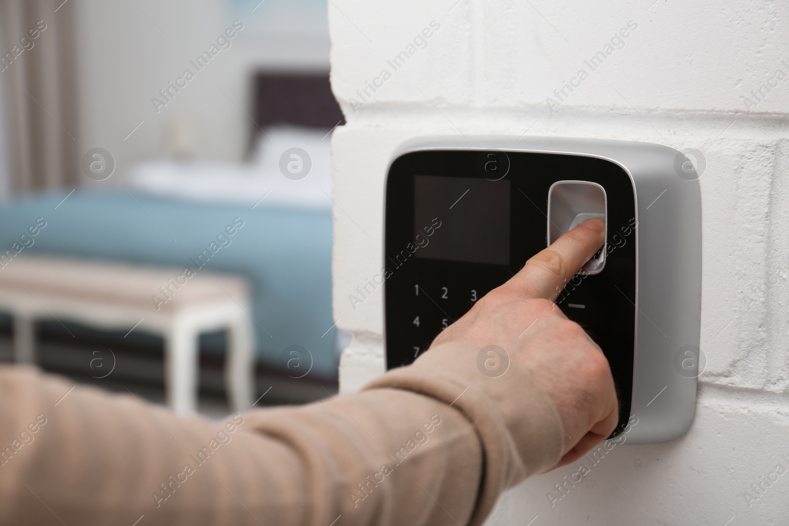 Photo of Man scanning fingerprint on alarm system at home, closeup