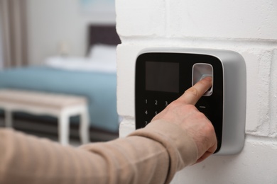 Man scanning fingerprint on alarm system at home, closeup