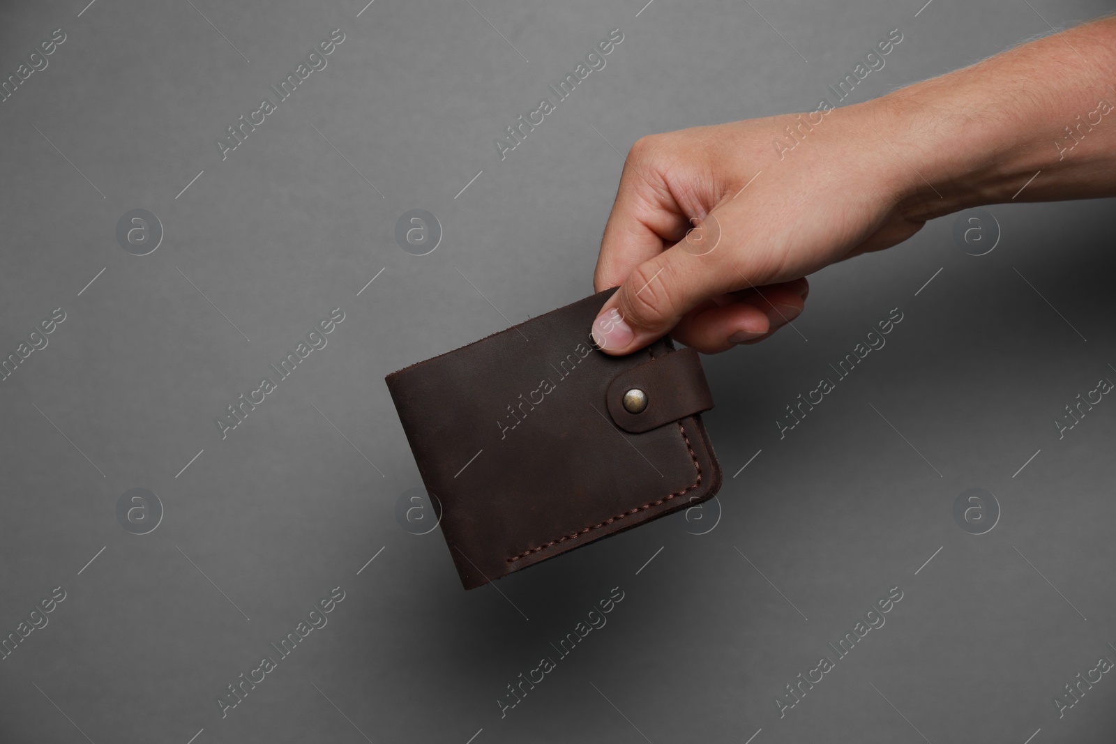 Photo of Man holding black leather wallet on dark grey background, closeup. Space for text