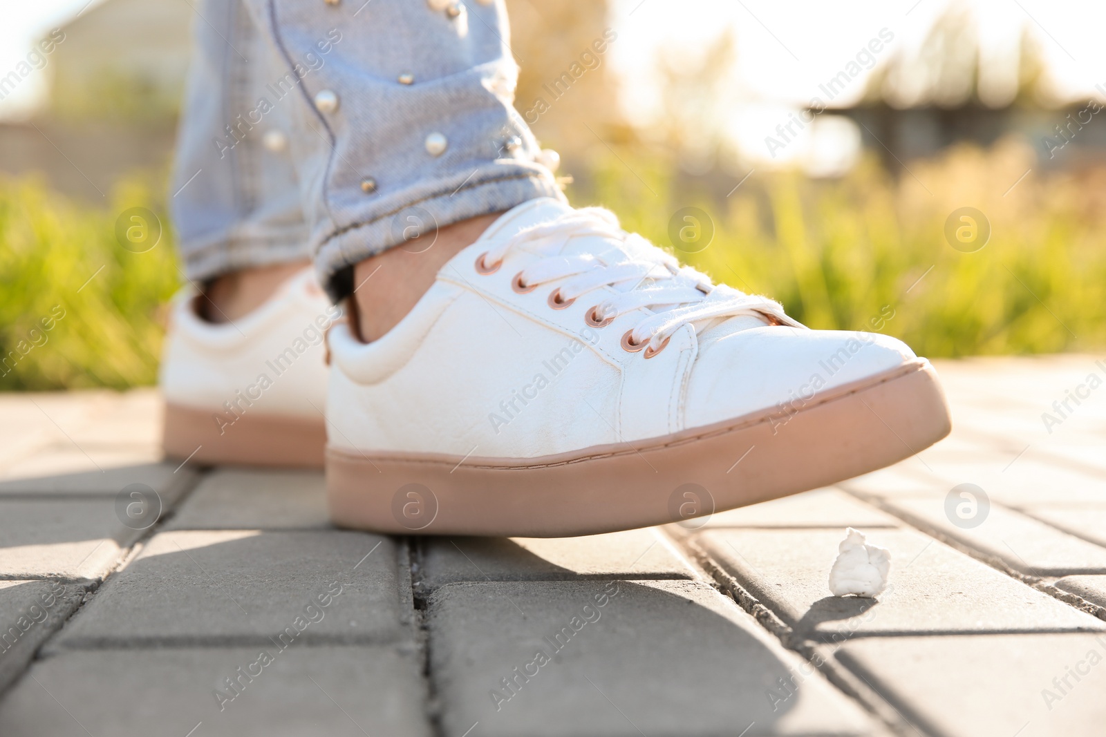 Photo of Woman stepping in chewing gum on sidewalk. Concept of stickiness