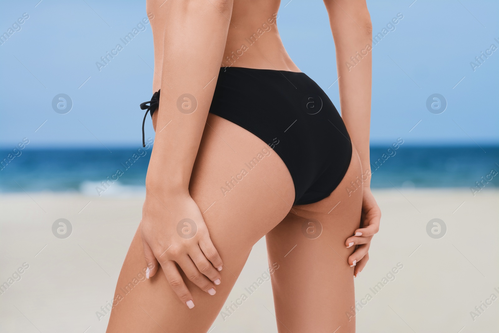 Image of Woman in stylish black bikini on sandy beach near sea, closeup