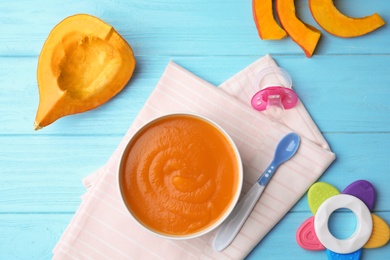 Flat lay composition with bowl of healthy baby food on wooden background
