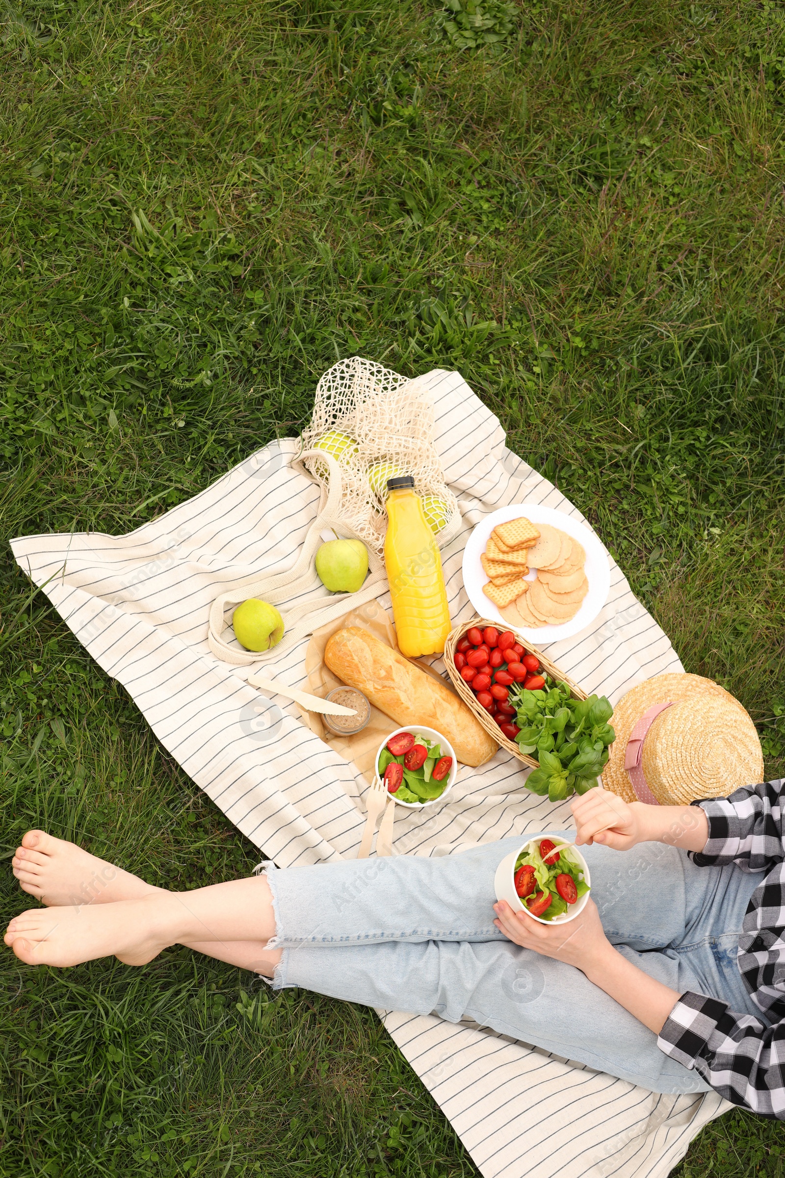 Photo of Girl having picnic on green grass in park, above view