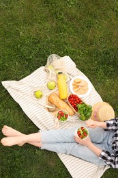 Girl having picnic on green grass in park, above view