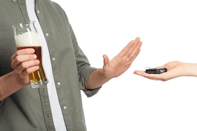 Man with glass of beer refusing drive car while woman suggesting him keys on white background, closeup. Don't drink and drive concept