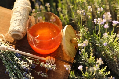 Photo of Jar of honey on wooden table in lavender field. Space for text