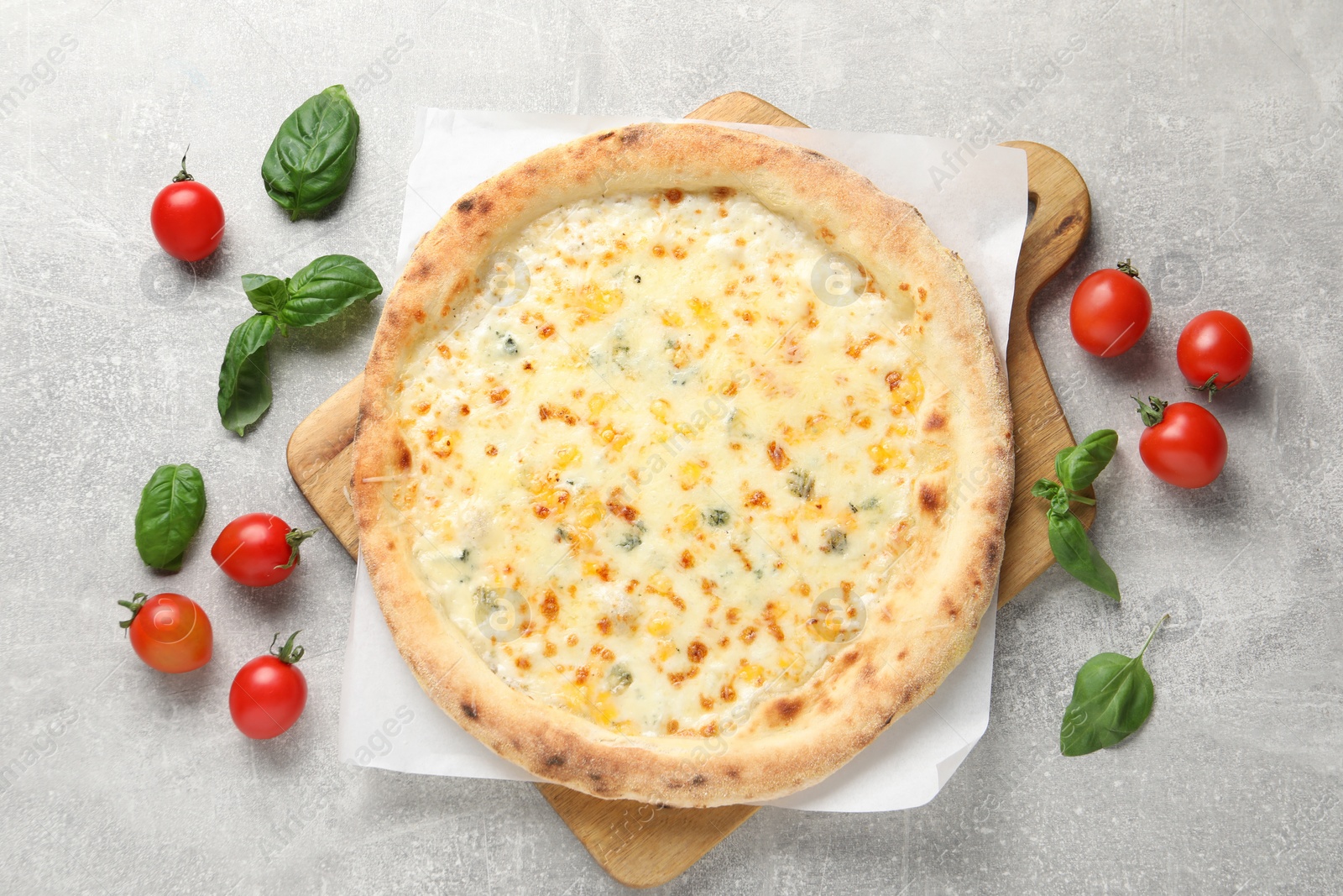 Photo of Delicious cheese pizza, basil and tomatoes on light grey table, flat lay