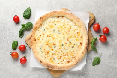 Photo of Delicious cheese pizza, basil and tomatoes on light grey table, flat lay