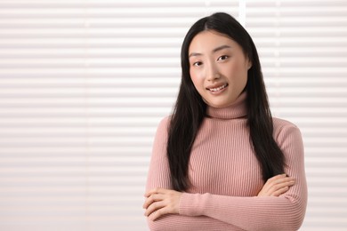 Portrait of smiling businesswoman with crossed arms in office. Space for text