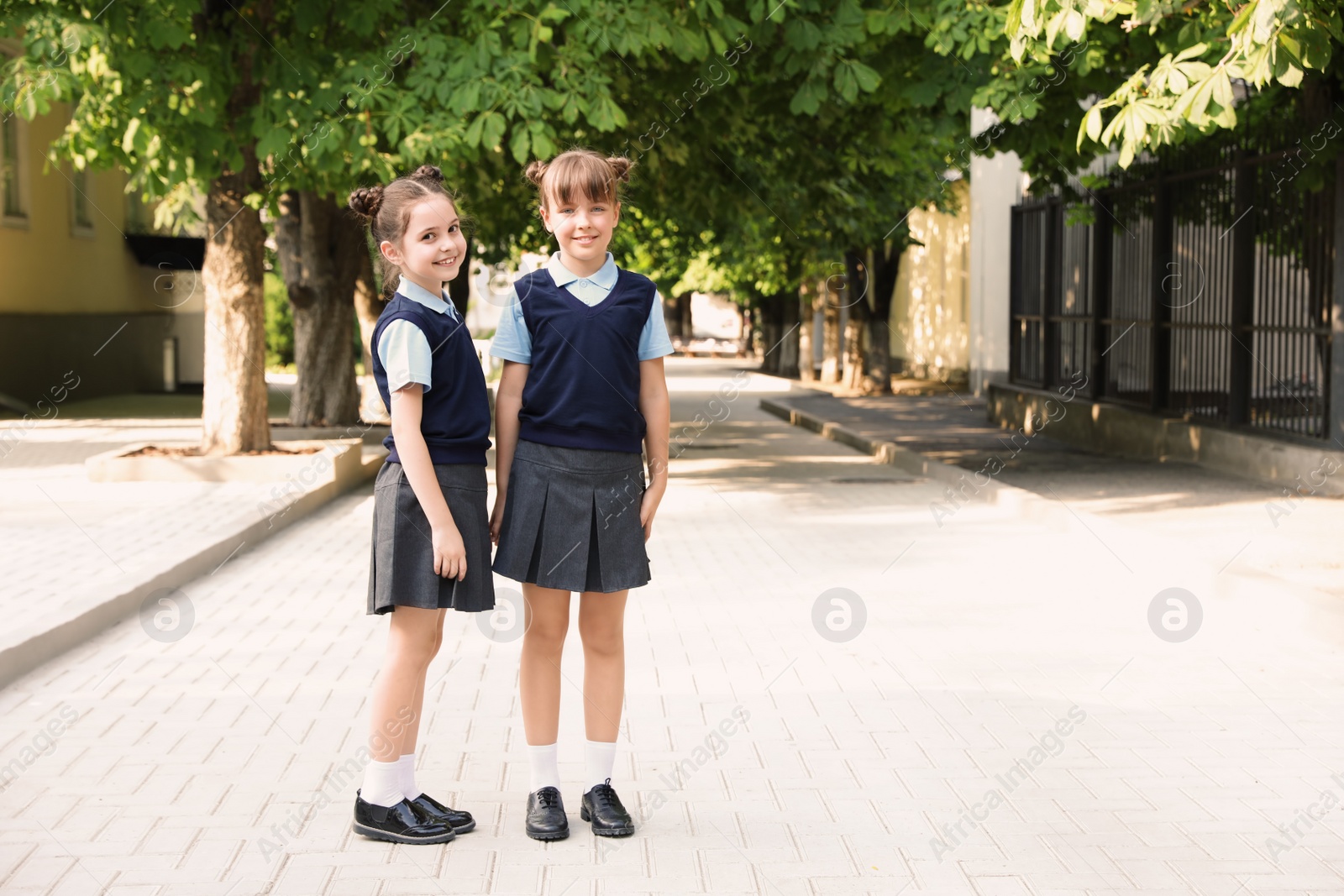 Photo of Little girls in stylish school uniform outdoors