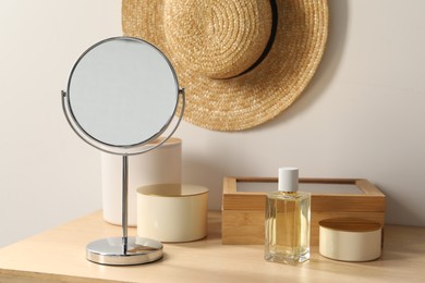 Mirror, perfume and accessories on makeup table in room