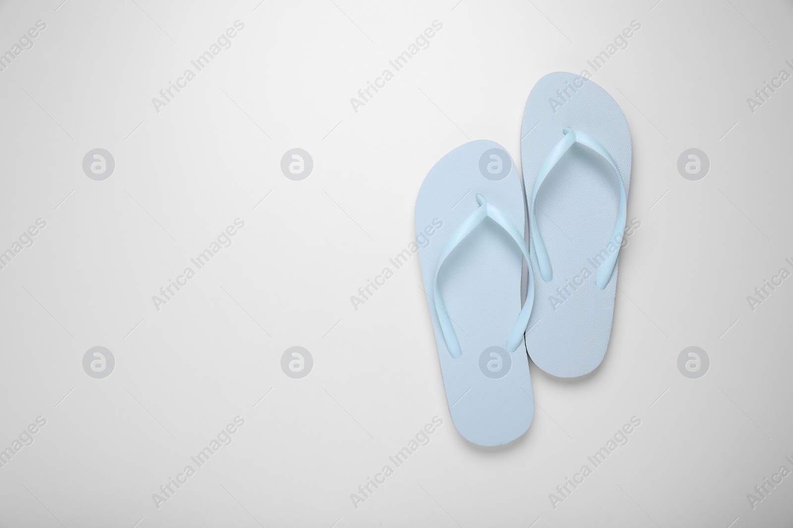 Photo of Light blue flip flops on white background, top view. Space for text