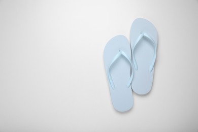 Light blue flip flops on white background, top view. Space for text