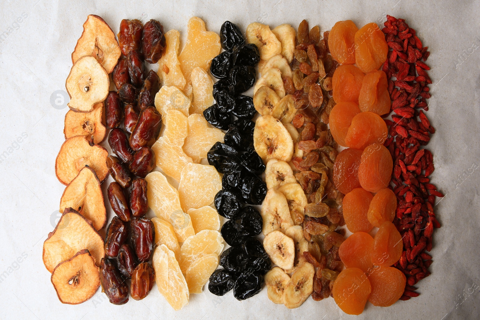 Photo of Different tasty dried fruits on paper, flat lay