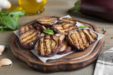 Photo of Delicious grilled eggplant slices served on wooden table, closeup