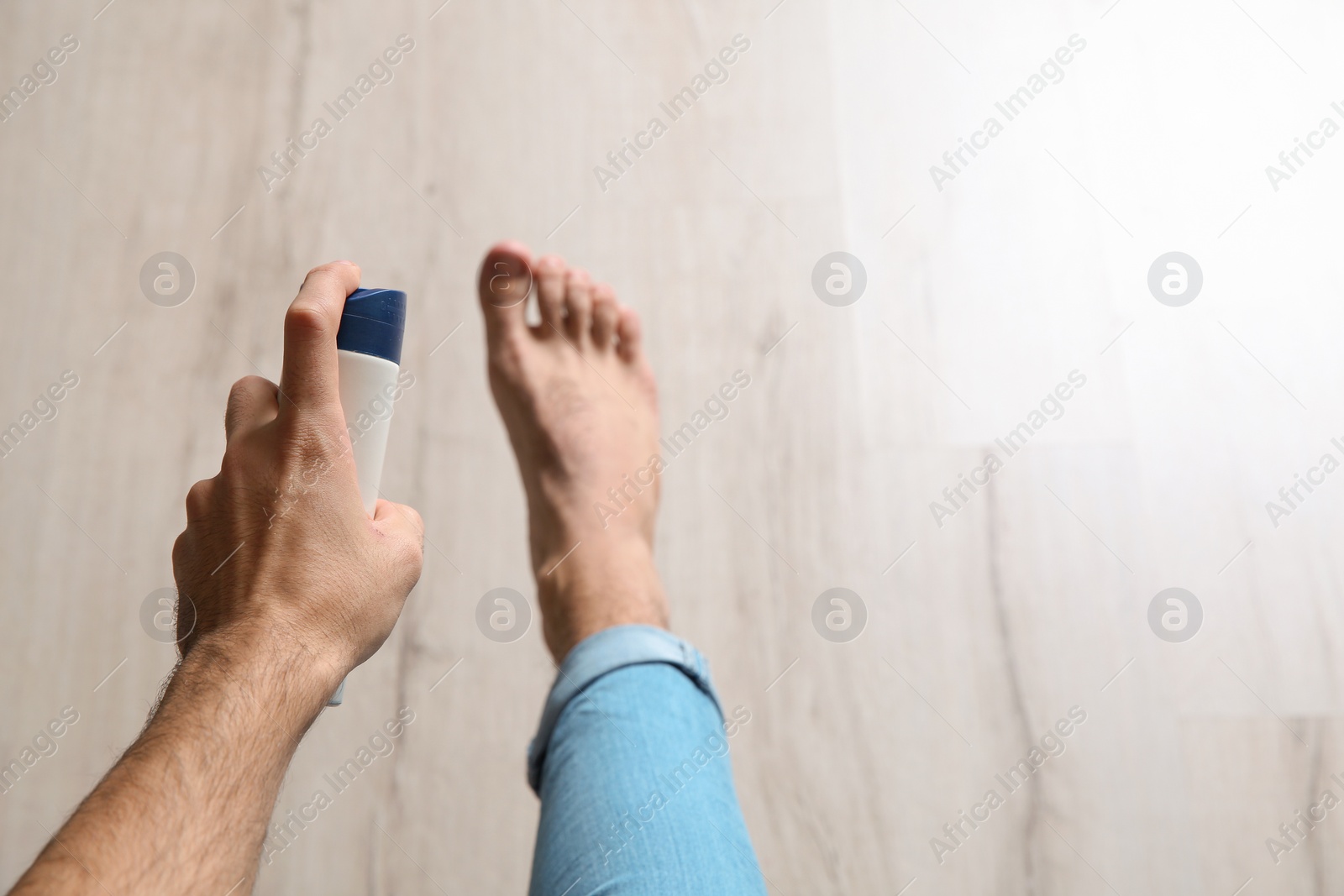 Photo of Young man using foot deodorant at home, closeup. Space for text