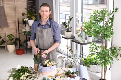 Photo of Male florist pruning rose at workplace