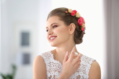 Photo of Beautiful young bride with bottle of perfume on blurred background