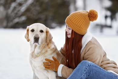 Beautiful young woman with adorable Labrador Retriever on winter day outdoors