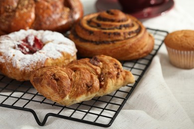 Photo of Different tasty freshly baked pastries on cooling rack, closeup