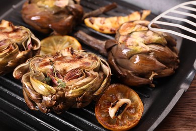 Photo of Tasty grilled artichokes on table, closeup view