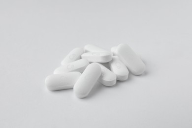 Photo of Pile of calcium supplement pills on white background, closeup