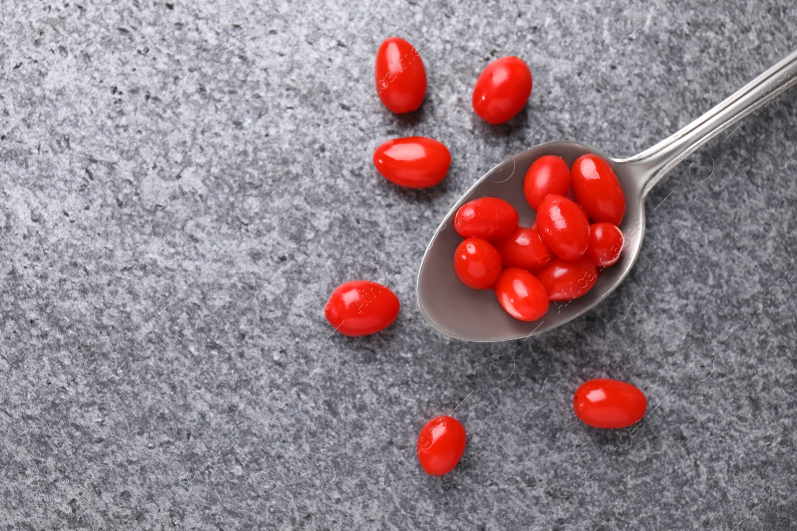 Photo of Spoon with fresh goji berries on grey background, flat lay. Space for text