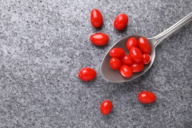 Spoon with fresh goji berries on grey background, flat lay. Space for text