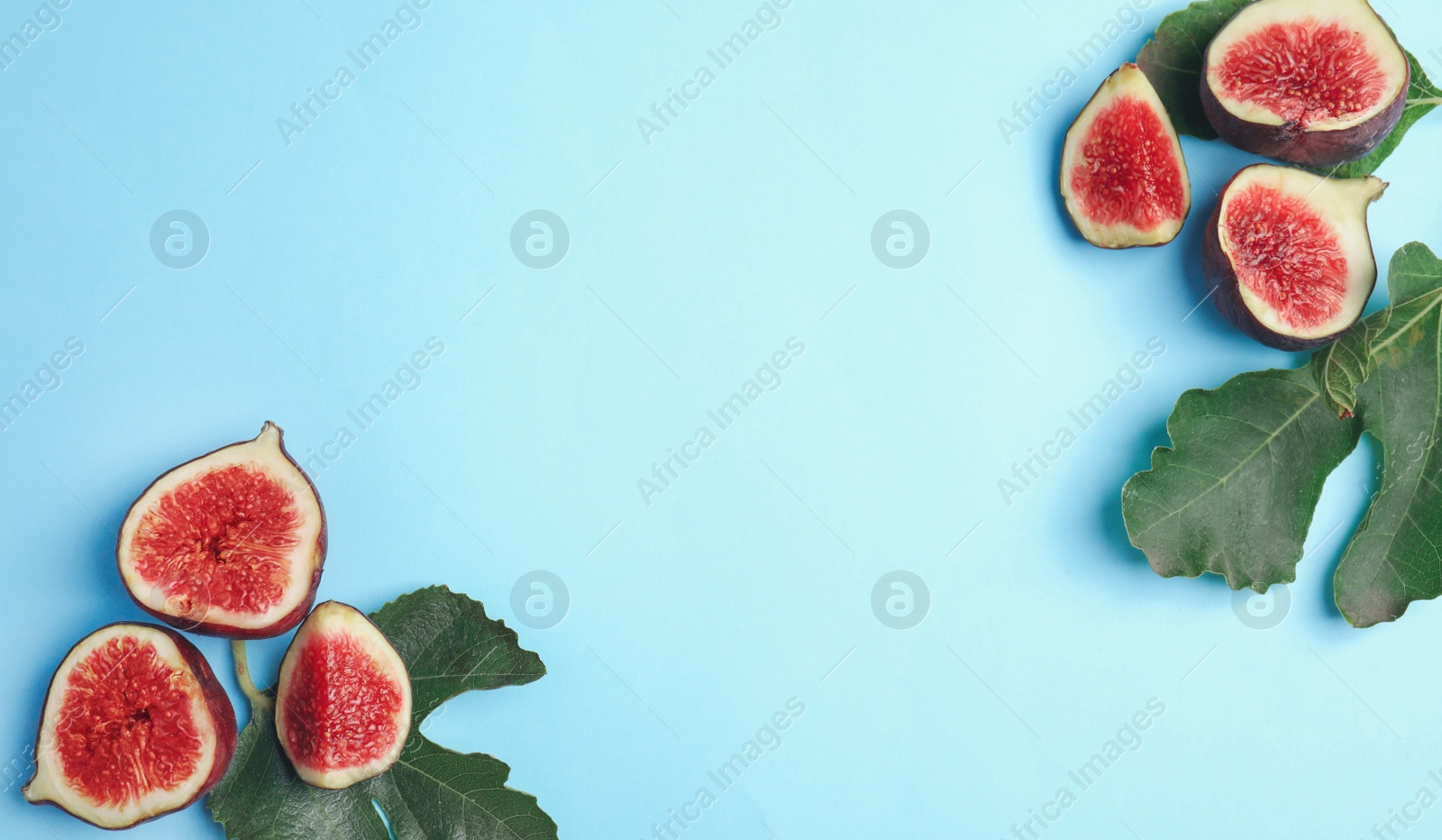 Photo of Delicious ripe figs and green leaves on light blue background, flat lay. Space for text