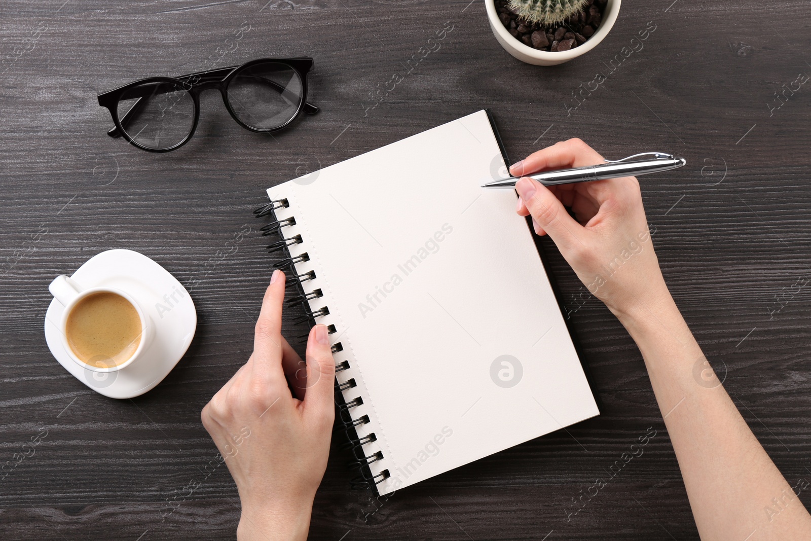 Photo of Woman with notebook and pen at grey wooden table, top view. Space for text