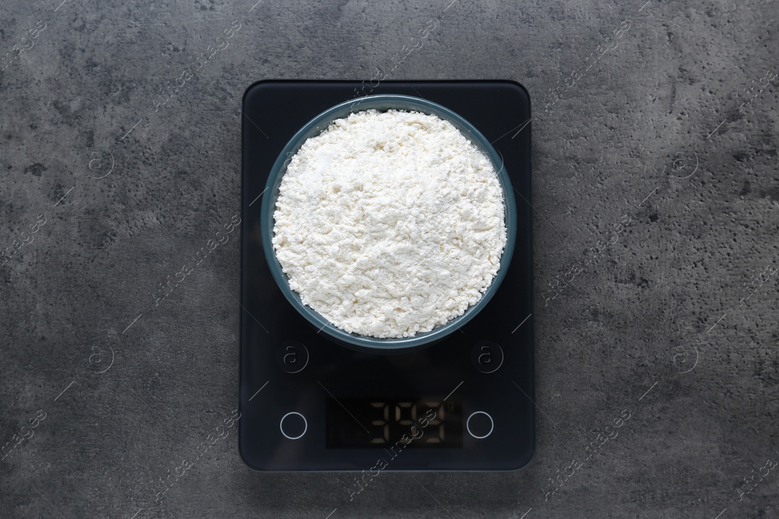 Photo of Electronic scales with flour on grey table, top view